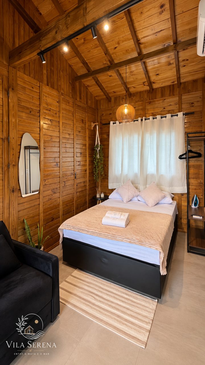 Estúdio 4: cama de casal e poltrona preta no quarto de madeira